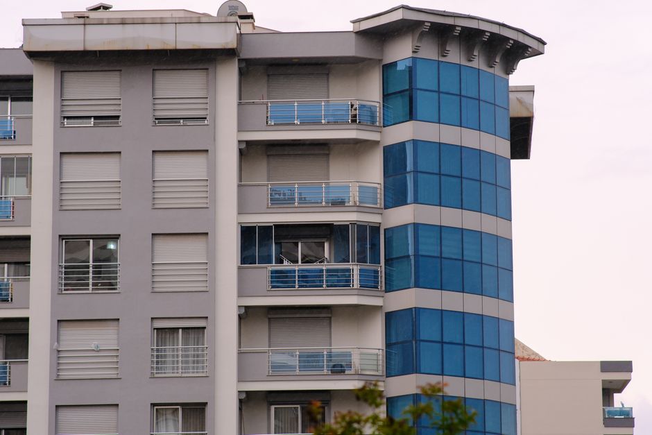 Suvremena fasada poslovne zgrade s plavim staklom i balkonima u Bornovi, İzmir